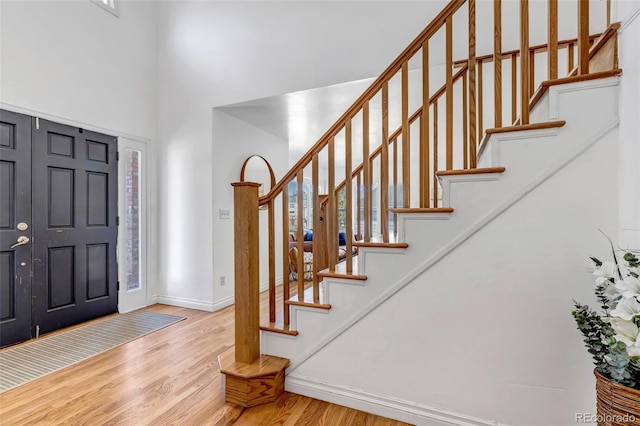 entrance foyer with stairway, a high ceiling, wood finished floors, and baseboards