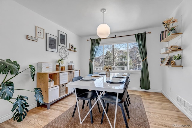 dining space with light wood-style floors, visible vents, and baseboards