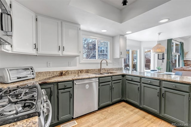 kitchen with a sink, stainless steel appliances, visible vents, and white cabinets