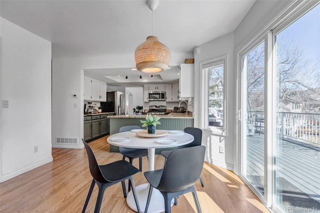 dining area with light wood-type flooring, baseboards, and visible vents