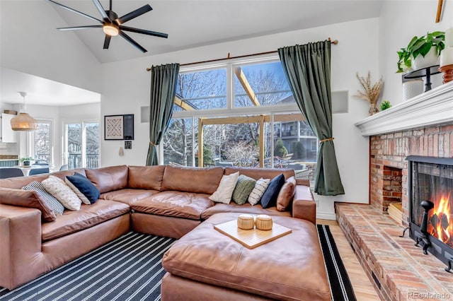 living room with lofted ceiling, a brick fireplace, wood finished floors, and a ceiling fan