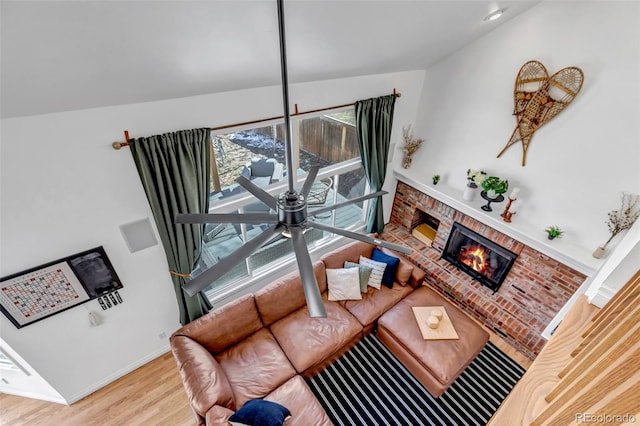 living room featuring a brick fireplace, wood finished floors, and baseboards