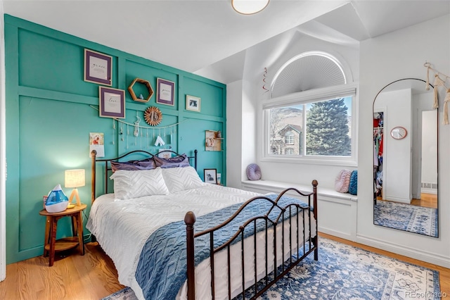 bedroom with baseboards, lofted ceiling, and light wood-style floors