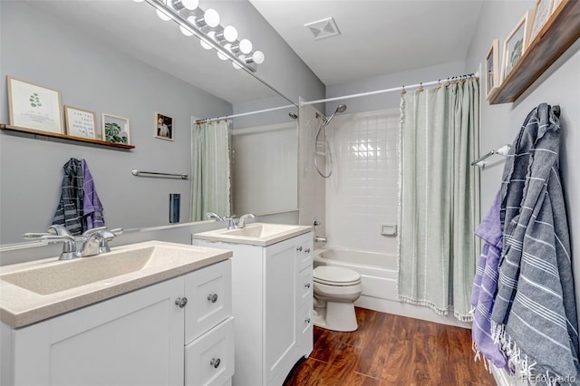 full bathroom with visible vents, toilet, wood finished floors, shower / bath combination with curtain, and vanity