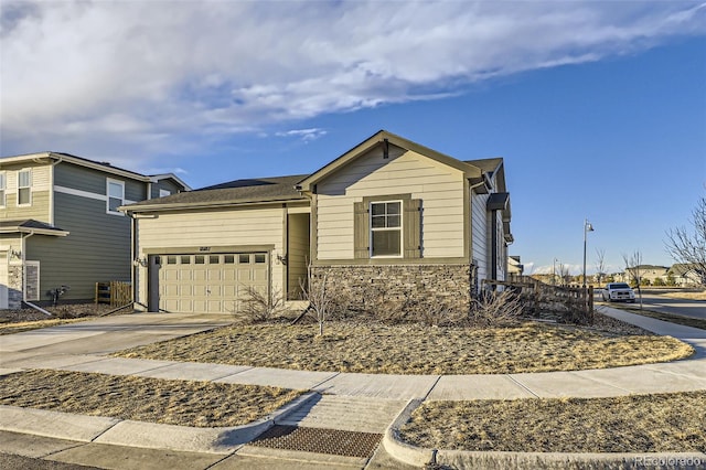 view of front facade with an attached garage, concrete driveway, and stone siding