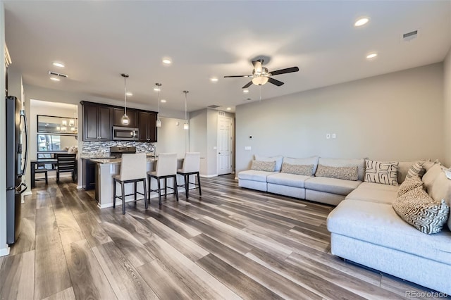 living area featuring ceiling fan, wood finished floors, visible vents, and recessed lighting