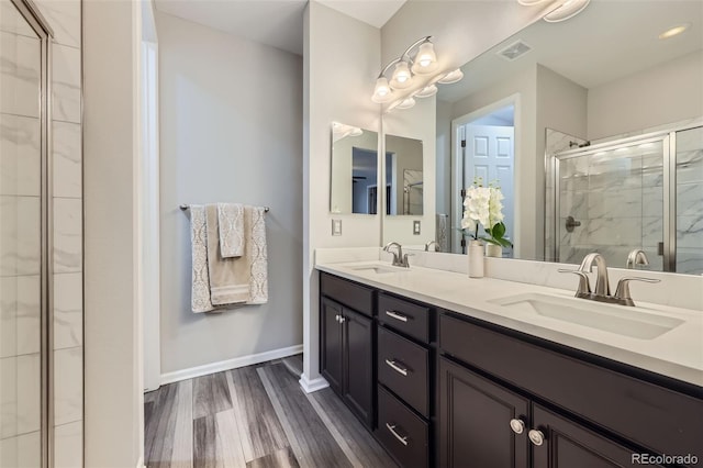 full bath with a shower stall, visible vents, a sink, and wood finished floors