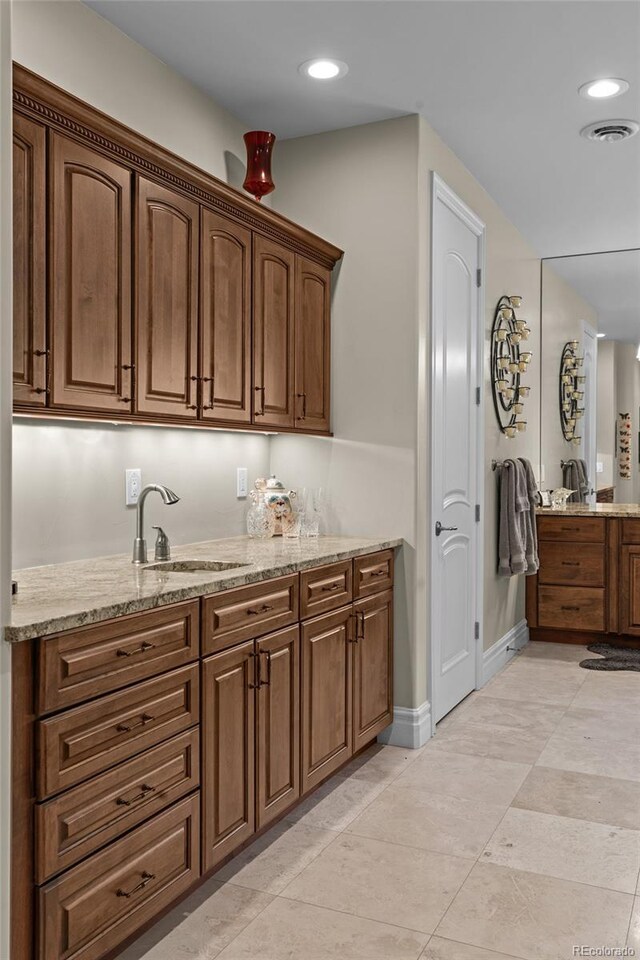 1160 Monaco Pkwy, Denver, CO 80220 - kitchen featuring light stone counters, recessed lighting, brown cabinetry, and light tile patterned flooring