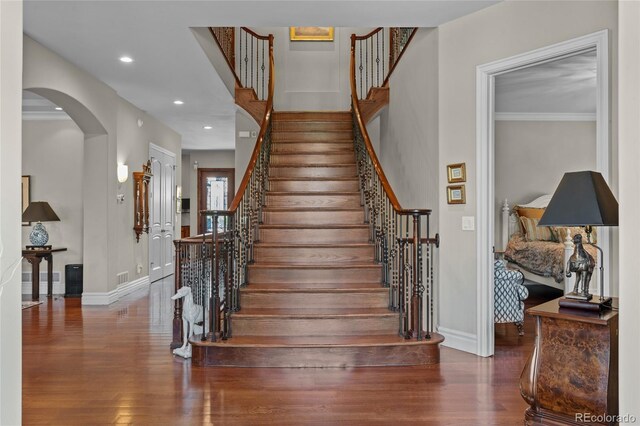 1160 Monaco Pkwy, Denver, CO 80220 - stairway featuring wood finished floors, arched walkways, recessed lighting, and crown molding