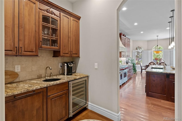 1160 Monaco Pkwy, Denver, CO 80220 - indoor wet bar featuring wine cooler, range with two ovens, decorative backsplash, light wood-style floors, and premium range hood