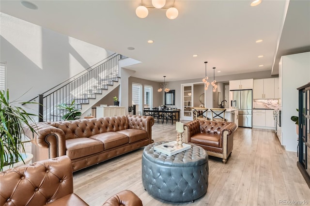 living room featuring stairway, an inviting chandelier, light wood-style flooring, and recessed lighting