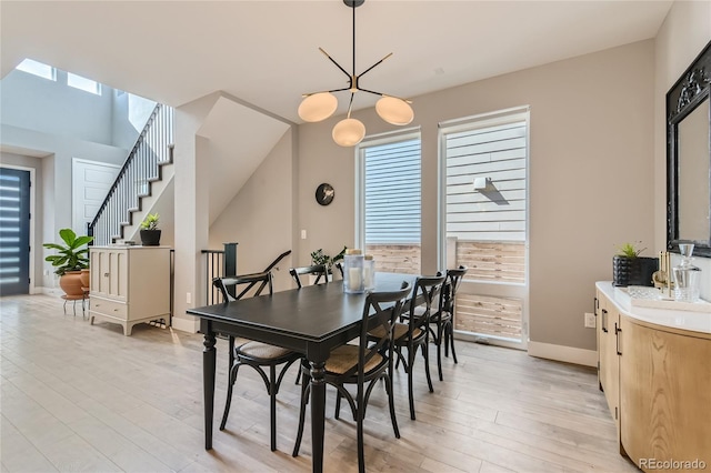 dining room featuring light wood-style floors, stairs, and baseboards