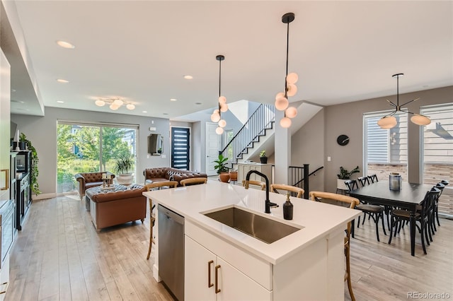 kitchen with a breakfast bar, open floor plan, a sink, and stainless steel dishwasher