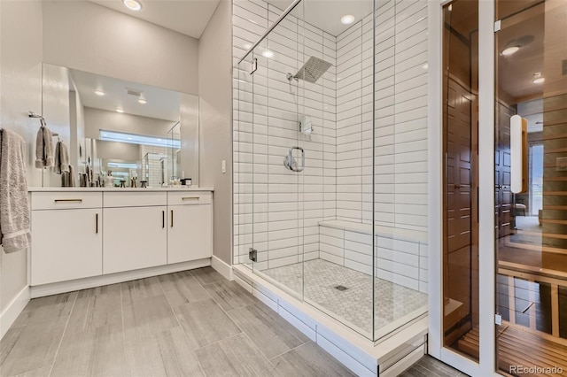 full bathroom featuring baseboards, a shower stall, and vanity