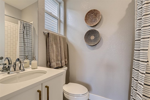 bathroom featuring toilet, a textured wall, curtained shower, and vanity