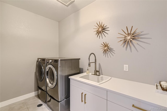 laundry area featuring light tile patterned floors, a sink, baseboards, cabinet space, and washing machine and clothes dryer