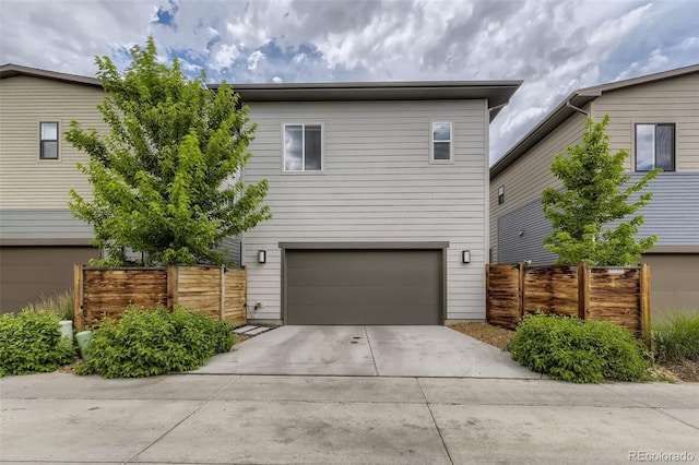 view of front of property with concrete driveway, an attached garage, and fence