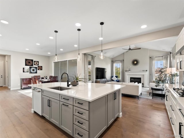 kitchen with light countertops, a fireplace, gray cabinets, and a sink