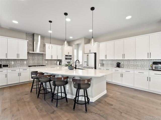 kitchen with a kitchen breakfast bar, white appliances, wall chimney range hood, and a sink