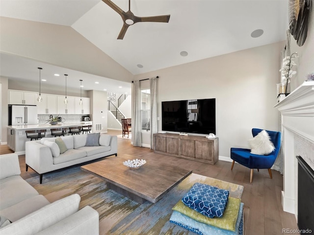 living room featuring stairway, a ceiling fan, baseboards, light wood-style flooring, and a fireplace