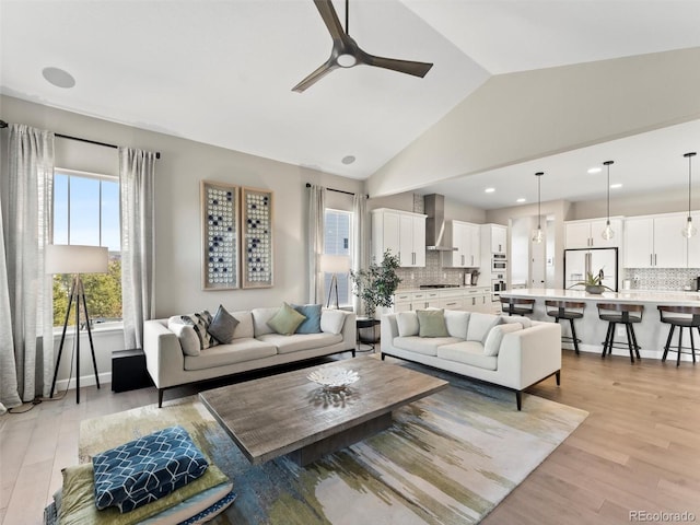 living area featuring light wood finished floors, baseboards, lofted ceiling, recessed lighting, and a ceiling fan