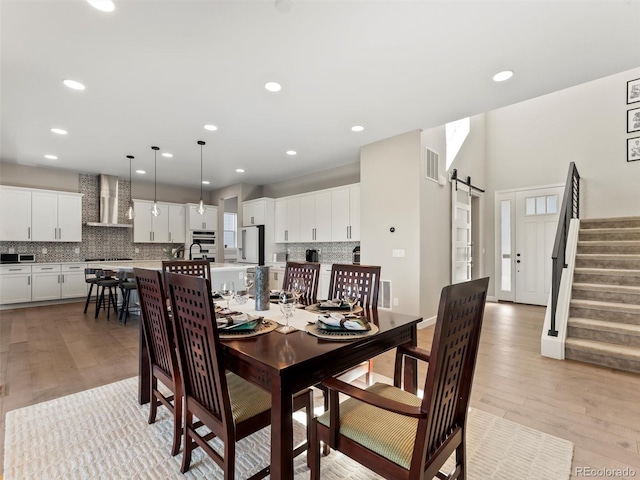 dining space with visible vents, stairway, a barn door, recessed lighting, and light wood-style floors