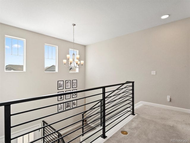 hall with an upstairs landing, carpet flooring, baseboards, and an inviting chandelier