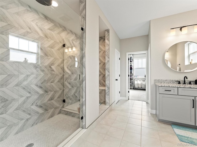 bathroom featuring a tile shower, tile patterned floors, vanity, and baseboards