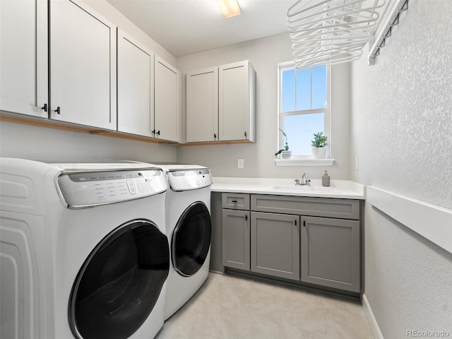 laundry area with washer and clothes dryer, cabinet space, a textured wall, and a sink