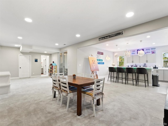 dining room featuring indoor wet bar, recessed lighting, light colored carpet, and baseboards