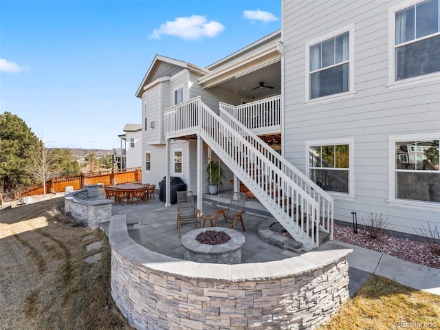 rear view of house featuring fence, a fire pit, a wooden deck, stairs, and a patio area