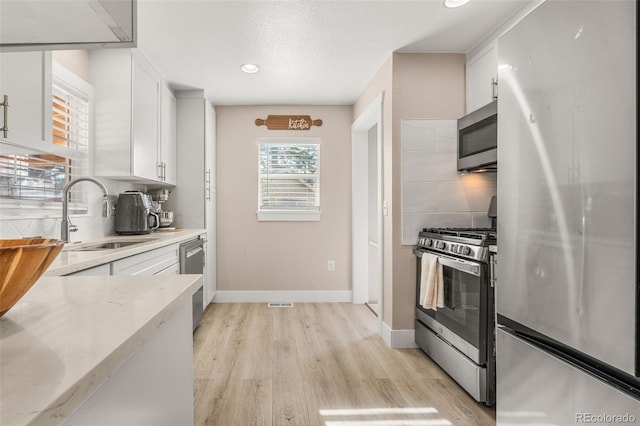 kitchen with white cabinets, appliances with stainless steel finishes, backsplash, and a sink