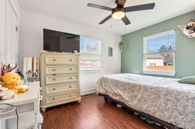 bedroom featuring dark wood-style floors, visible vents, baseboards, and a ceiling fan