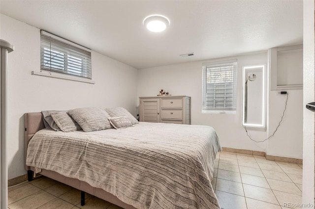 bedroom featuring light tile patterned floors, baseboards, and visible vents