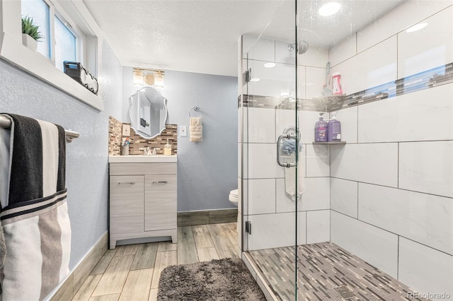 full bathroom featuring a textured ceiling, a textured wall, vanity, wood tiled floor, and a stall shower