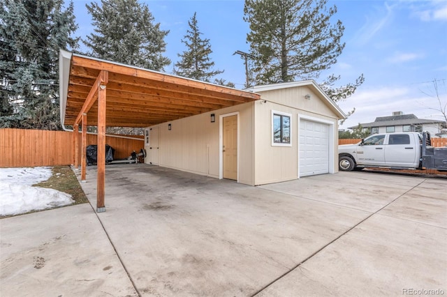 exterior space with an outbuilding, concrete driveway, and fence