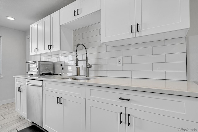 2544 S Raleigh St, Denver, CO 80219 - kitchen featuring a sink, decorative backsplash, and white cabinetry
