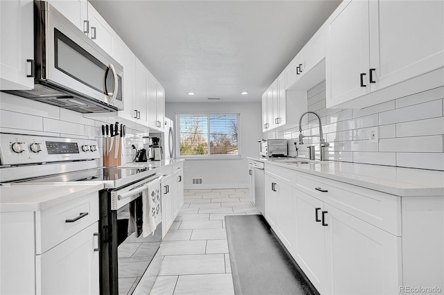2544 S Raleigh St, Denver, CO 80219 - kitchen featuring tasteful backsplash, baseboards, a sink, light countertops, and stainless steel appliances