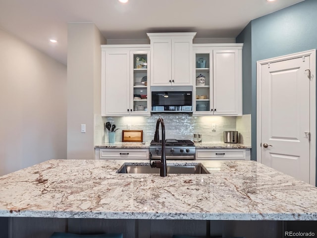 kitchen featuring stainless steel microwave, white cabinetry, and decorative backsplash