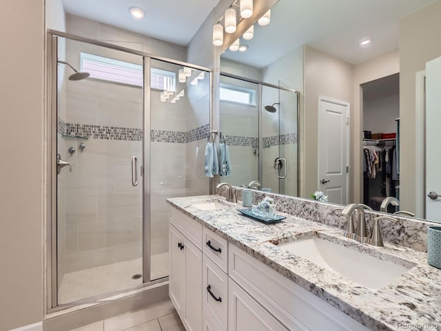 full bathroom featuring double vanity, a stall shower, and a sink