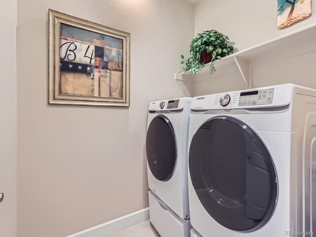 laundry area with tile patterned flooring, laundry area, separate washer and dryer, and baseboards