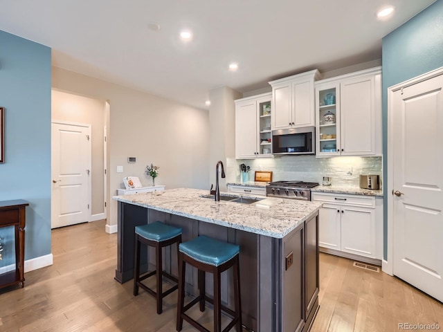 kitchen featuring a sink, backsplash, appliances with stainless steel finishes, and white cabinets