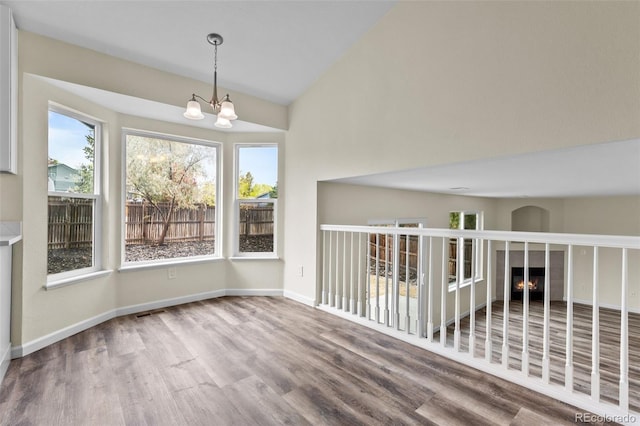 interior space with a notable chandelier, hardwood / wood-style floors, and lofted ceiling