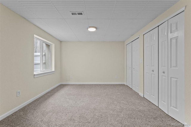 unfurnished bedroom featuring carpet and two closets