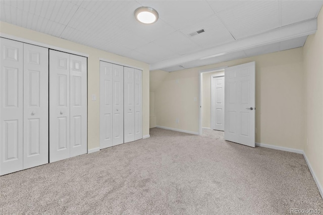 unfurnished bedroom with carpet floors and two closets