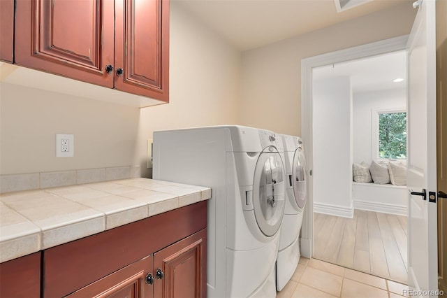 washroom featuring cabinets, separate washer and dryer, and light tile patterned floors