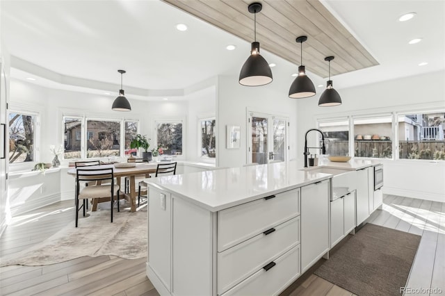 kitchen with an island with sink, light countertops, and light wood finished floors