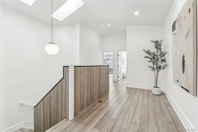 interior space featuring baseboards, recessed lighting, lofted ceiling with skylight, an upstairs landing, and light wood-type flooring