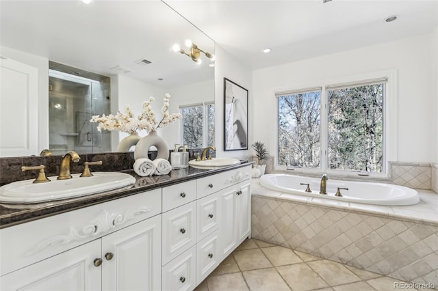 full bathroom featuring tile patterned floors, a bath, double vanity, and a sink