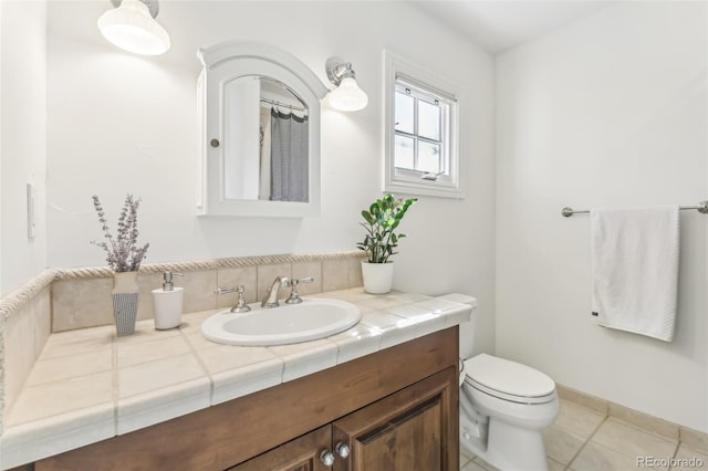 bathroom with tile patterned flooring, toilet, vanity, and baseboards